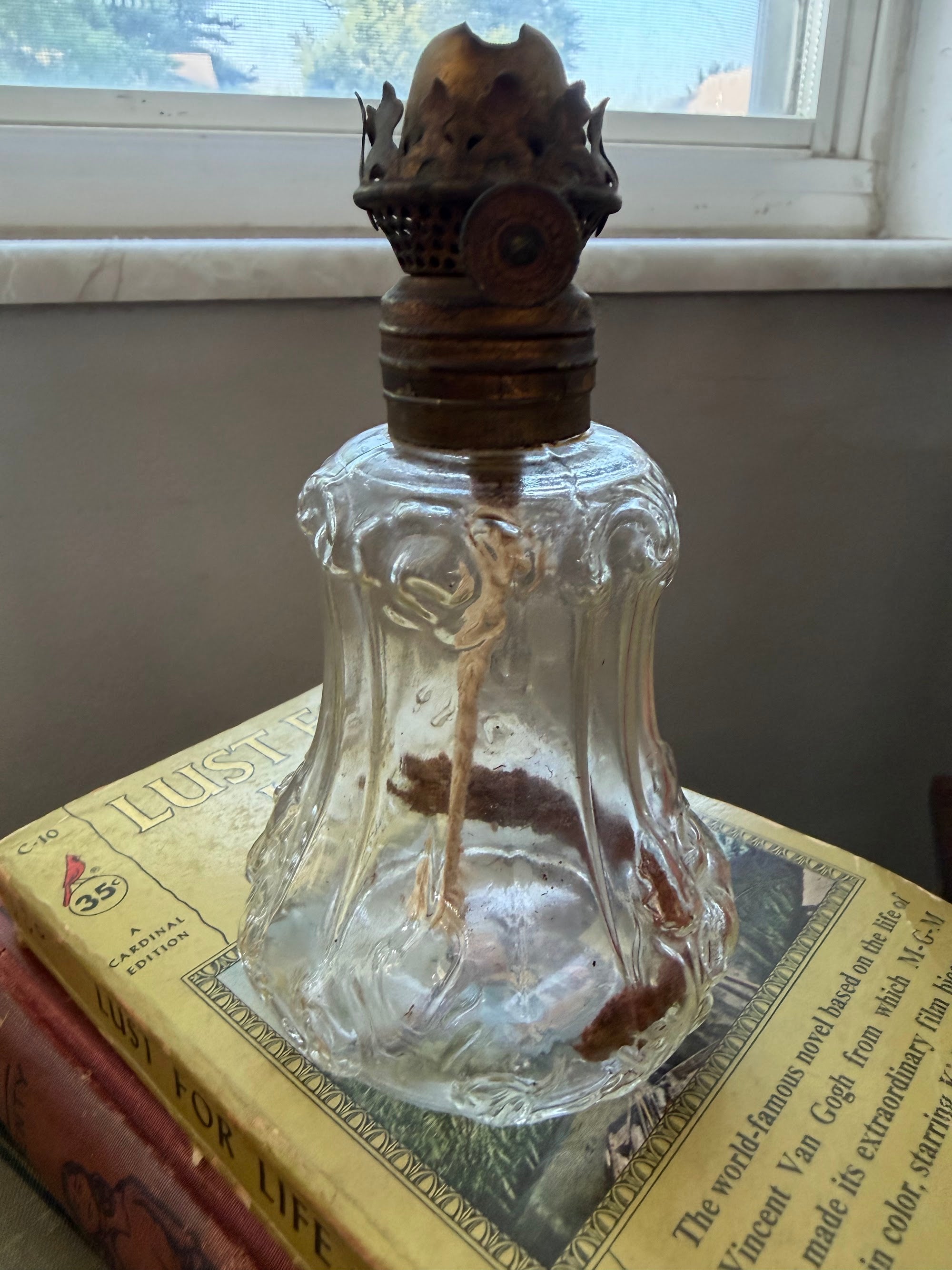 Antique miniature clear glass oil lamp with brass burner and wick, front view