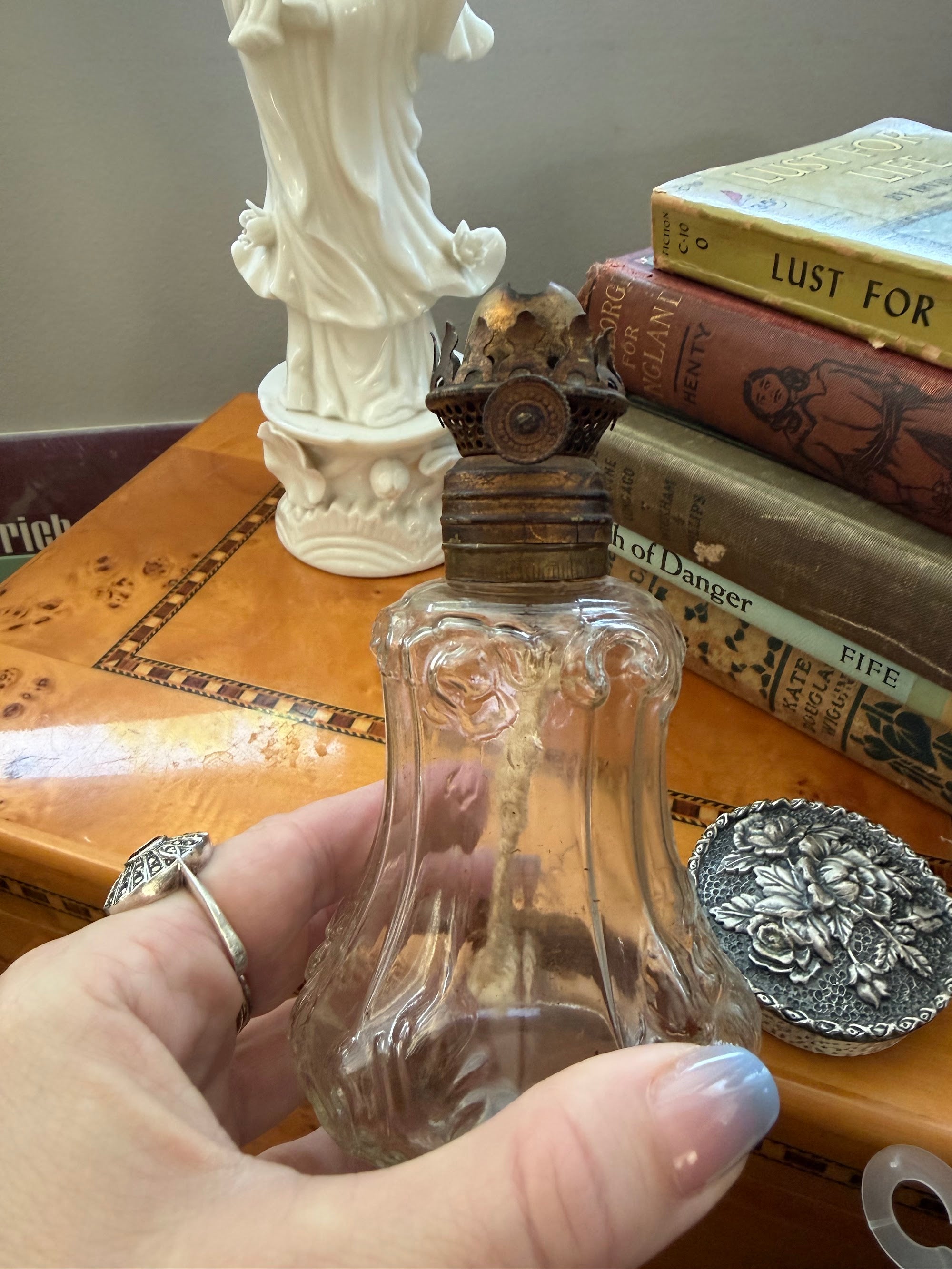 Hand holding miniature oil lamp showing scale