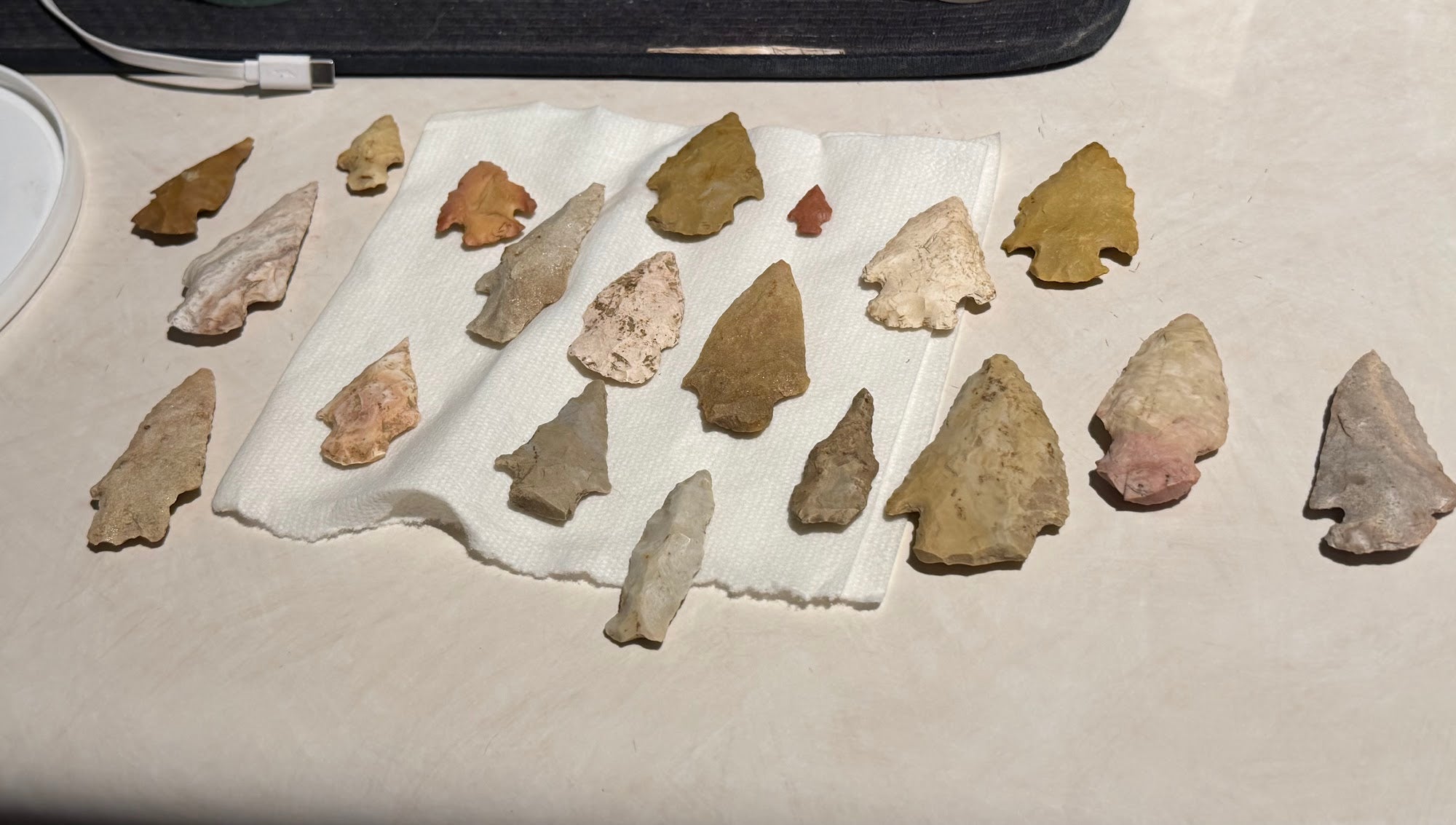 Collection of 16 knapped stone arrowhead points in varied sizes and materials
