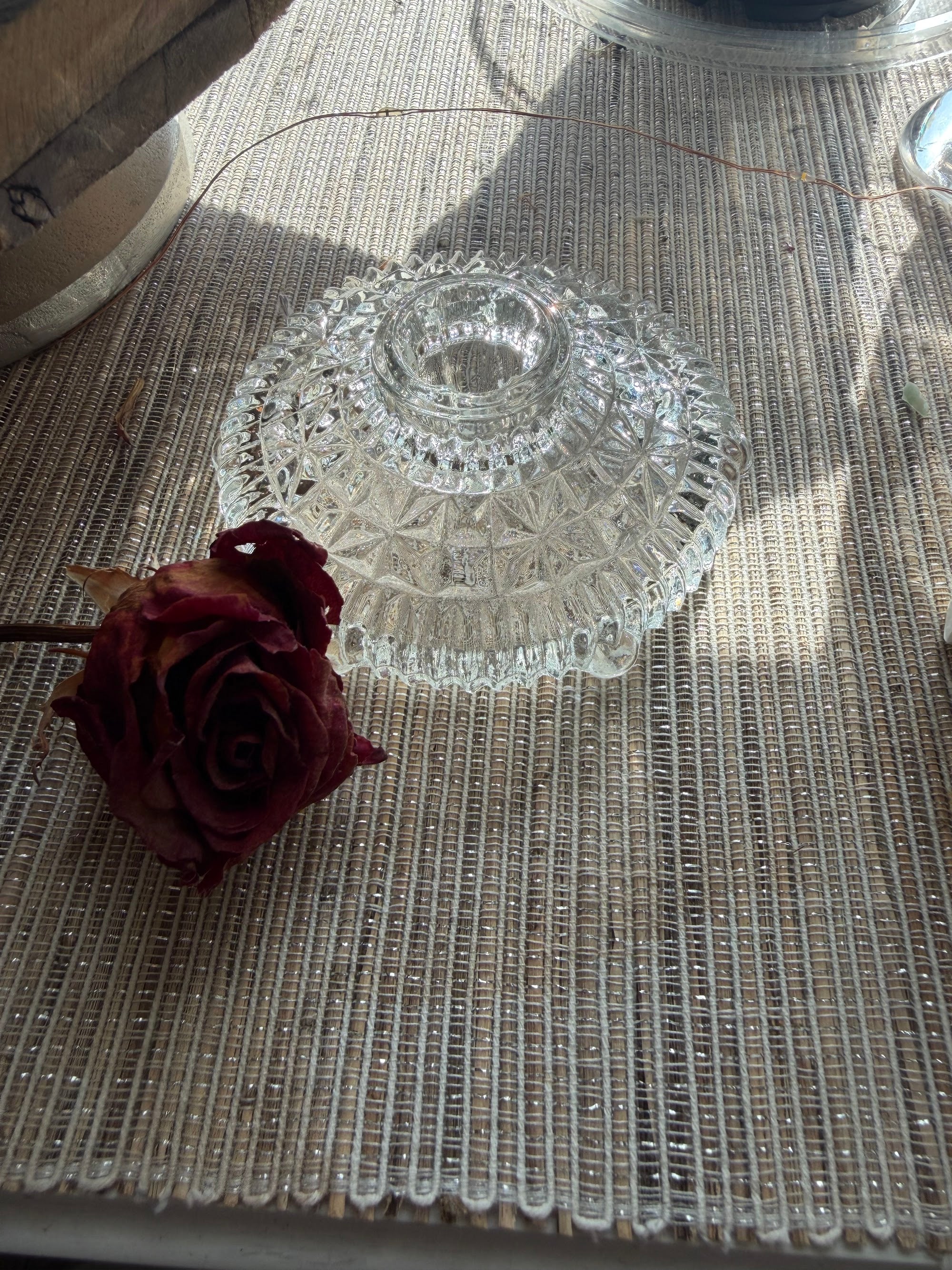 Pressed glass candle holder beside a dried red rose