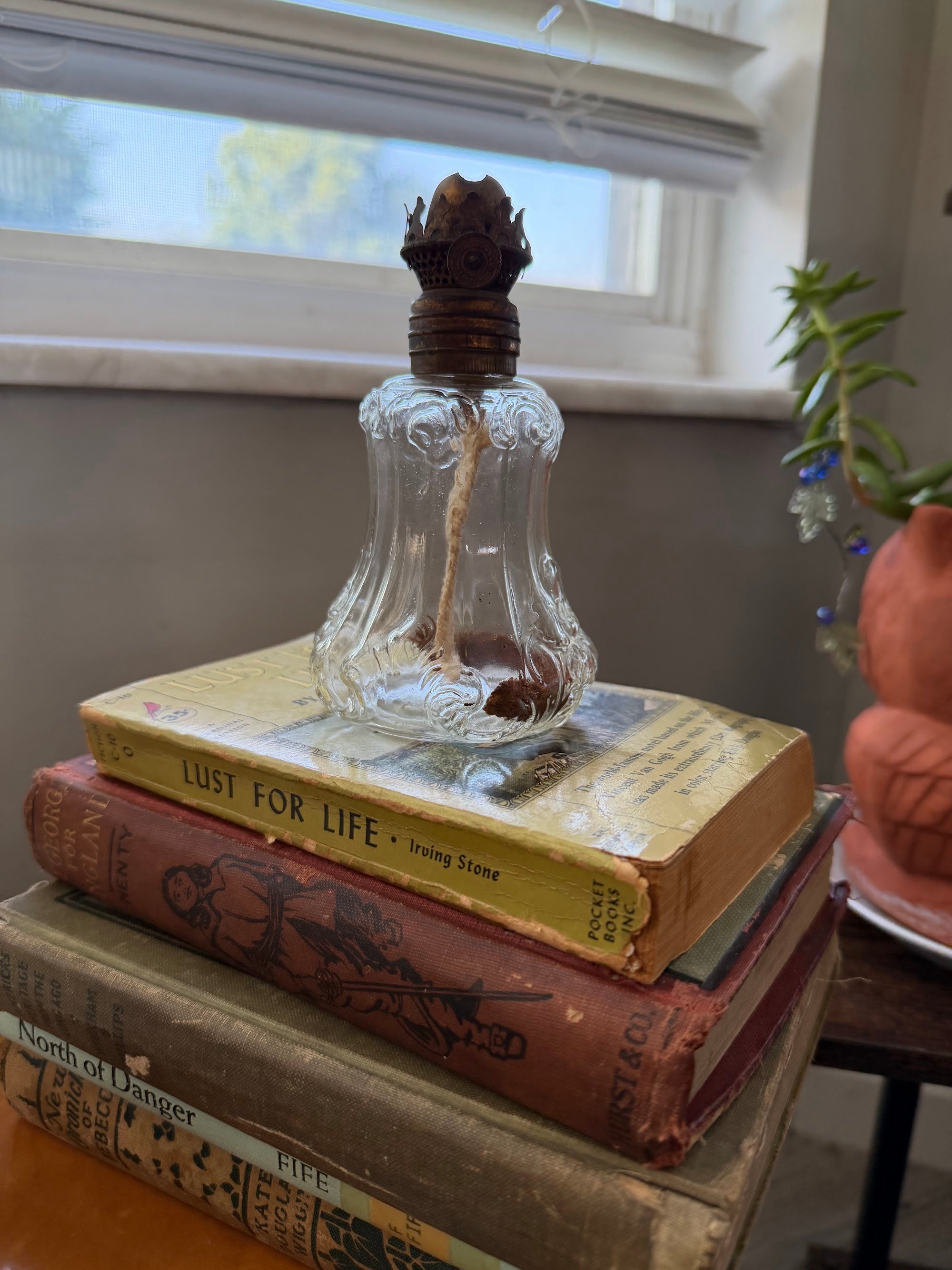 Miniature oil lamp displayed on vintage books
