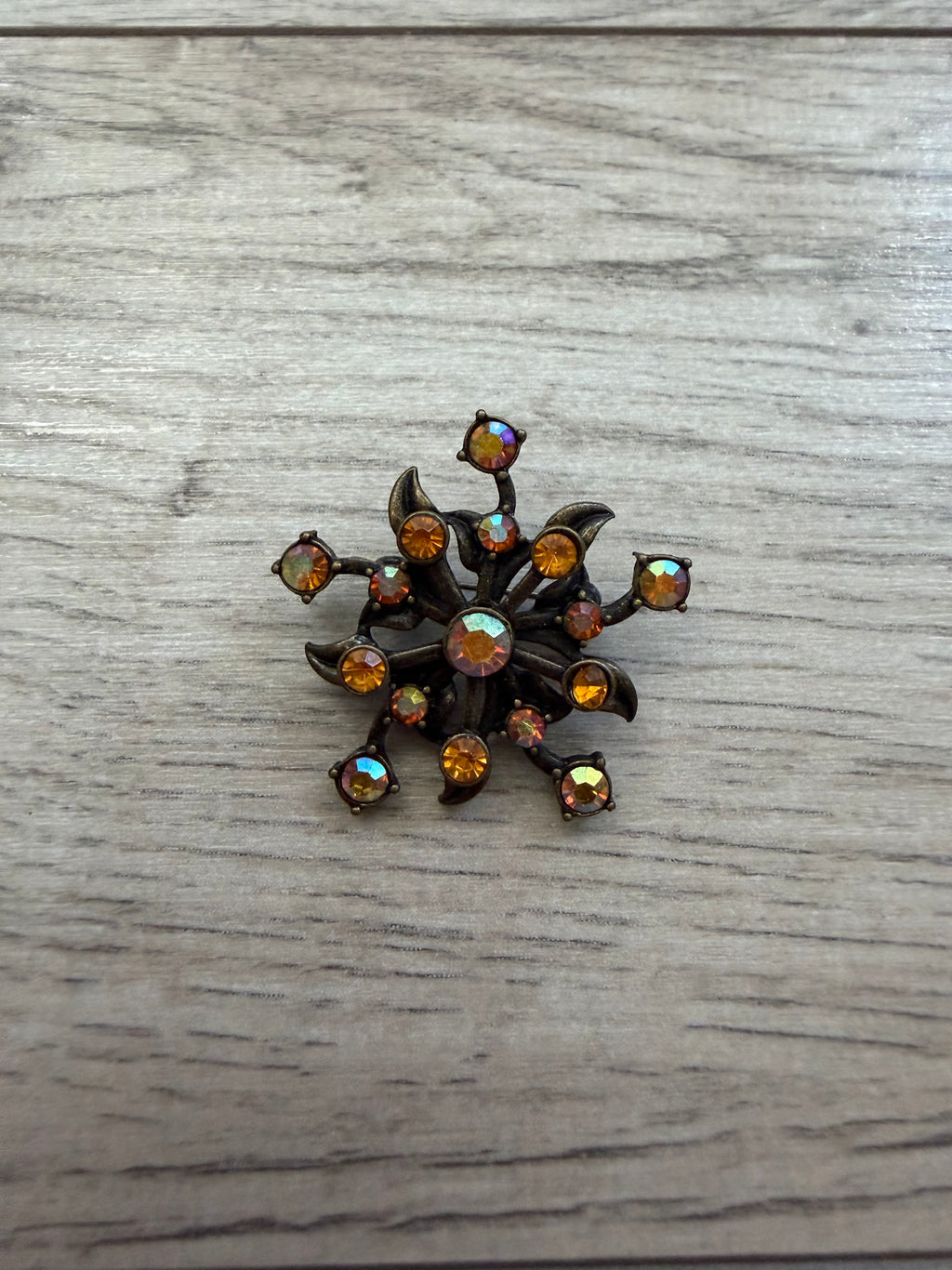 Close view of atomic flower brooch showing prong-set stones on dark metal