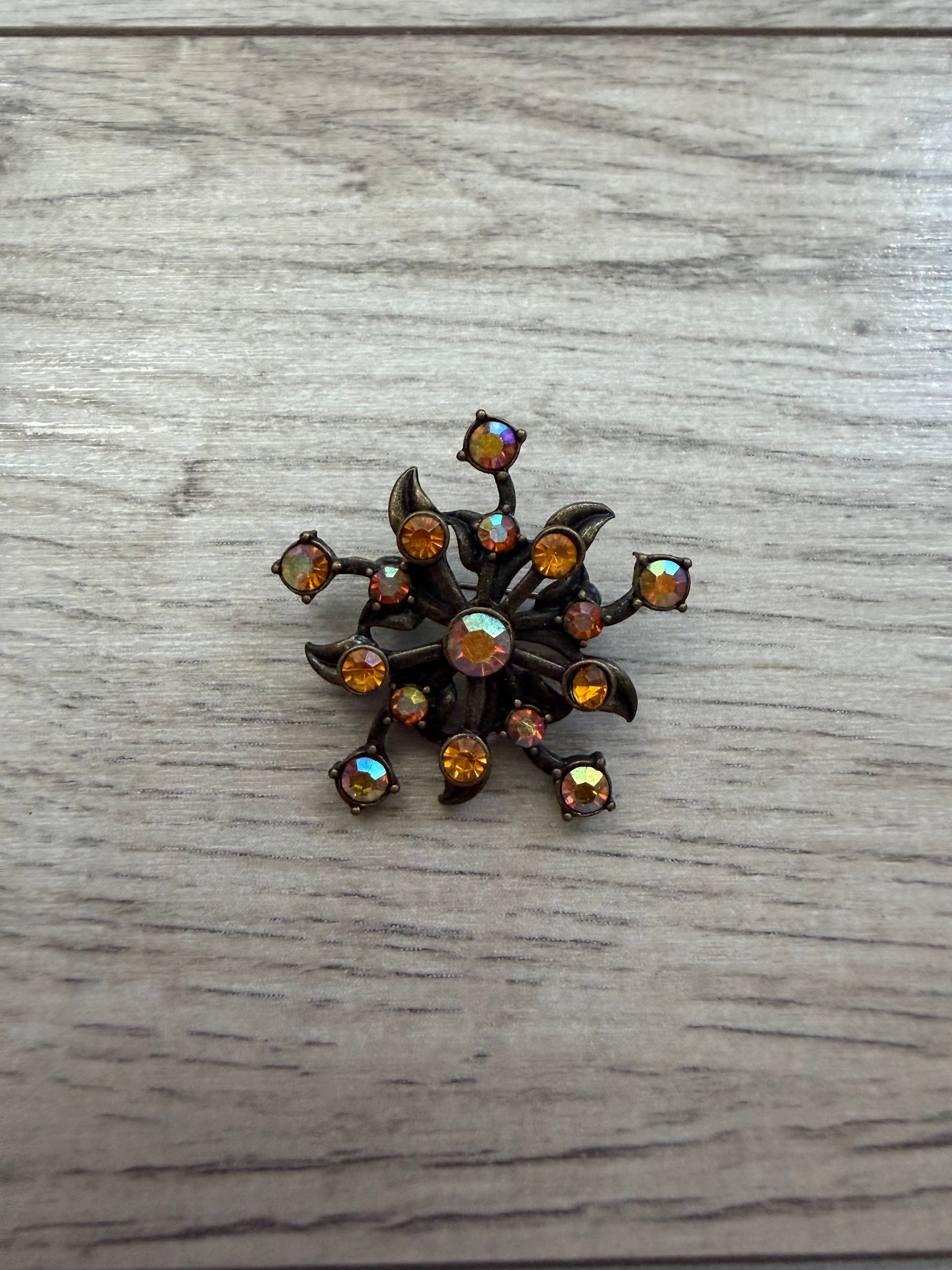 Close view of atomic flower brooch showing prong-set stones on dark metal
